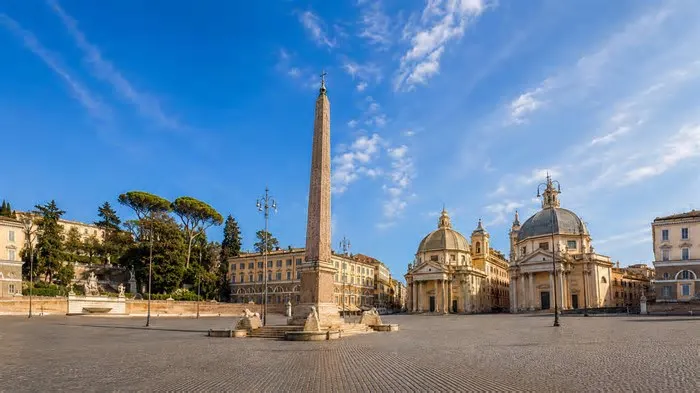 Roma aparece aqui numa ampla praça histórica, com destaque para um impressionante obelisco antigo no centro. A cena também ...